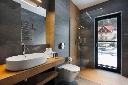 La salle de bains est pourvue d'un lavabo, de toilettes et d'une fenêtre. dans l'établissement PARK APARTAMENTY Krynica Zdrój, à Krynica-Zdrój