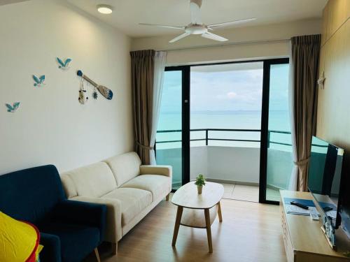 a living room with a couch and a view of the ocean at Mutiara Melaka Beach Resort by Minso in Tangga Batu