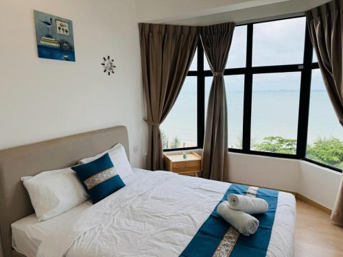 a bedroom with a bed with a view of the ocean at Mutiara Melaka Beach Resort by Minso in Tangga Batu
