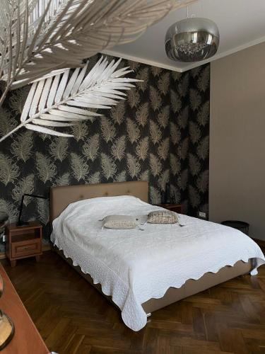 a bedroom with a white bed with a wall at 555 метров до моря in Liepāja