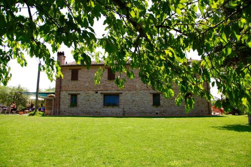 a large brick building in a field of grass at Agriturismo Biologico Villa Rosa in Monte Guiduccio