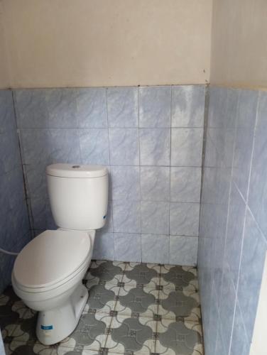une salle de bain avec toilettes et un mur carrelé dans l'établissement BALE LANGGAK COTTAGES, à Kuta Lombok