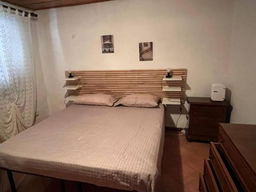 - une chambre avec un grand lit et une tête de lit en bois dans l'établissement L'angolo del Barbacane, à Terricciola