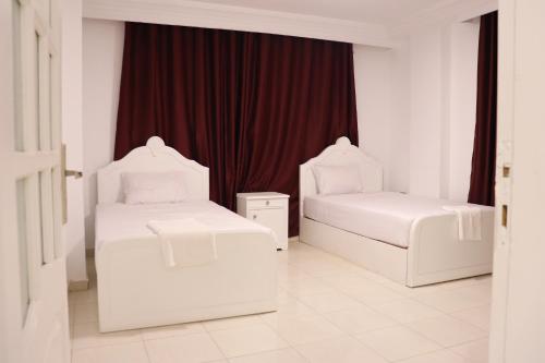 two white beds in a room with a red curtain at Falcon heaven in 6th Of October