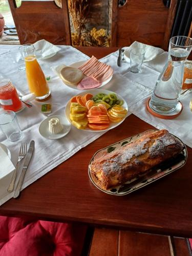 a table with a meal of meat and fruit on it at Oficina Do Joe Guesthouse in Outeiro
