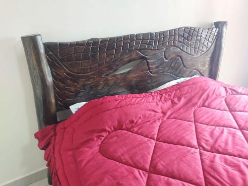 uma cama com lençóis cor-de-rosa e uma cabeceira de cama em madeira em Prince Studio @ Twiga House em Kigali