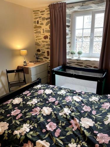 - une chambre avec un lit doté d'un couvre-lit floral et d'une fenêtre dans l'établissement Maison La pierre du lezard, à Laurie