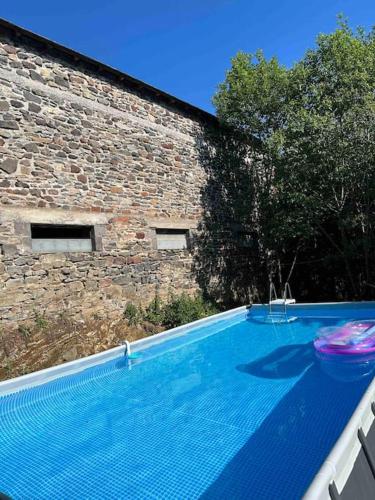 - une piscine avec un frisbee à côté d'un bâtiment en briques dans l'établissement Maison La pierre du lezard, à Laurie