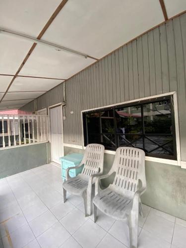 two white chairs and a table on a patio at INTAN CHALEt in Pangkor