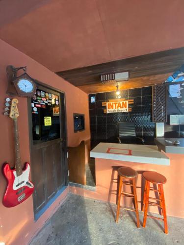 a kitchen with a counter and two stools and a guitar at INTAN CHALEt in Pangkor