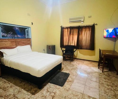 1 dormitorio con cama, mesa y escritorio en Adrenaline Lodge and Tours, en Livingstone