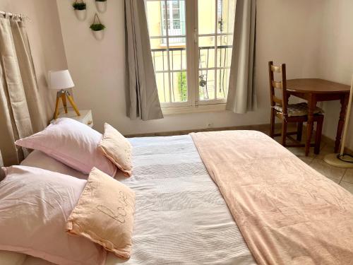 een slaapkamer met een bed met kussens en een raam bij Chambre indépendante à Lezignan-la-Cèbe in Lézignan-la-Cèbe