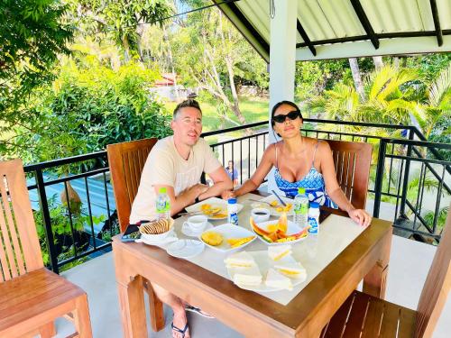 a man and woman sitting at a table with food at Oragan Resort in Tissamaharama