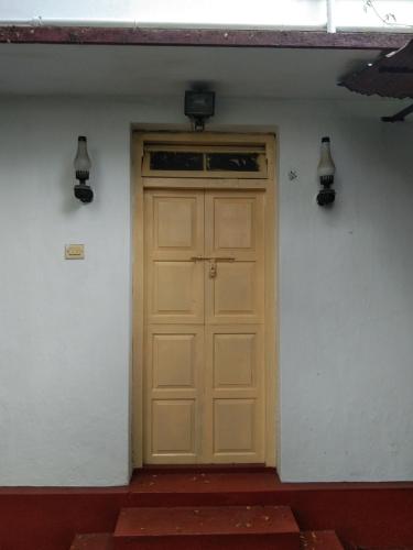 una puerta de madera en una pared blanca con dos luces en C. L Inn, en Kochi