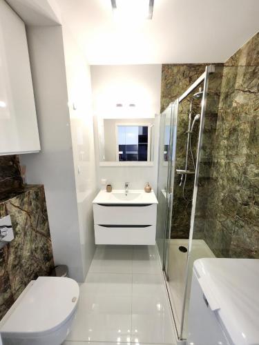 a bathroom with a toilet and a sink and a shower at Słoneczny Apartament Warsaw Spire in Warsaw