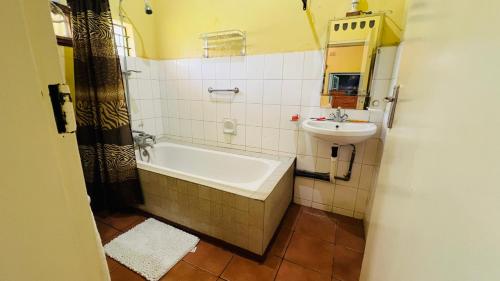 a bathroom with a bath tub and a sink at Adrenaline Lodge and Tours in Livingstone