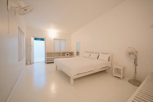 a white bedroom with a bed and a fan at Beach at the White House in Udupi