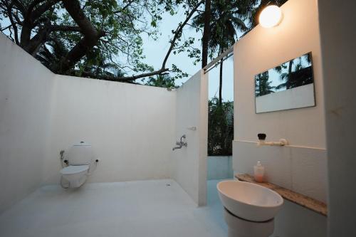 a bathroom with a toilet and a sink and a tree at Beach at the White House in Udupi