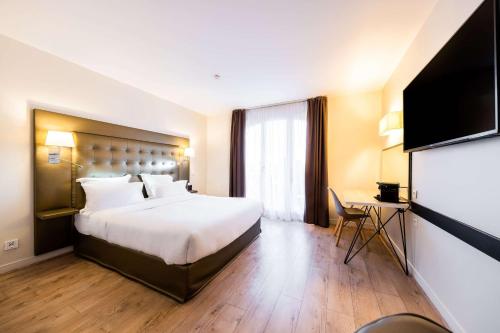 a hotel room with a large bed and a flat screen tv at Hôtel Quality Suites Maisons-Laffitte Paris Ouest in Maisons-Laffitte