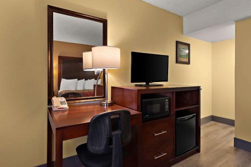 a hotel room with a desk with a television and a bed at Kings House Motor Hotel in Flagstaff