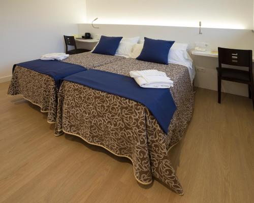 a bedroom with a bed with blue sheets and a desk at Hotel Roma in Sarria