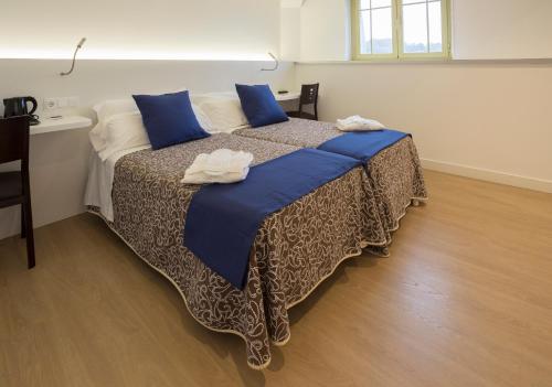 a bedroom with a large bed with blue pillows at Hotel Roma in Sarria