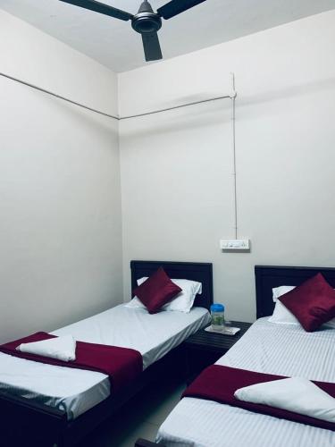 2 camas en una habitación con paredes blancas y almohadas rojas en M square residency, en Kalpetta
