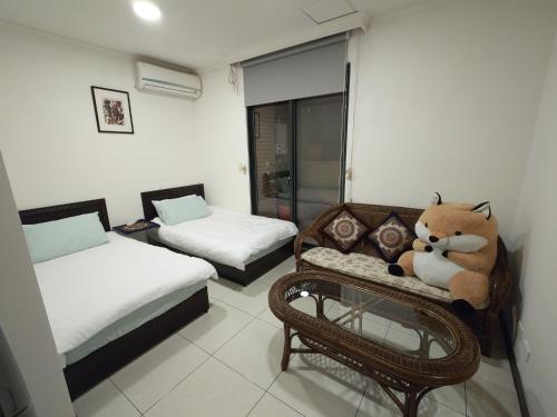 een kamer met 2 bedden en een teddybeer op een bank bij Cat5 Mewo Meow House in Taipei