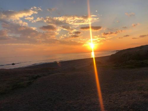 a sunset on a beach with the sun setting at Blu Pointe in Minamiboso