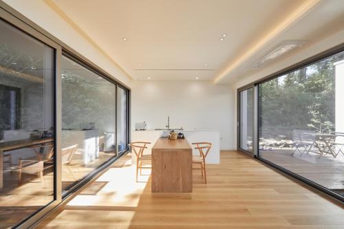 cocina y comedor con grandes ventanas y mesa en Mokha forest house, en Jeju