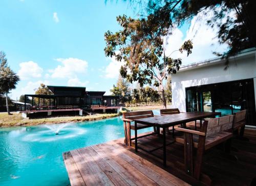 una terrazza in legno con tavolo e panche accanto alla piscina di Skybird lake view Resort&Camping Khaoyai a Khanong Phra