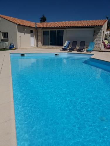 a large blue swimming pool in front of a house at Gîte du Midi de Saint-Porchaire - Charmante maison de vacances avec piscine chauffée in Saint-Porchaire