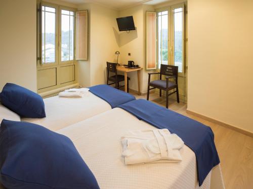 2 camas en una habitación con escritorio y silla en Hotel Roma, en Sarria