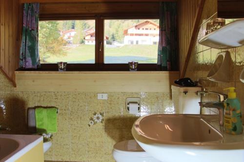 ラ・ヴィッラにあるCiasa Alfriのバスルーム(洗面台、トイレ付)、窓が備わります。