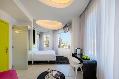 a hotel room with a bedroom with a bed and a table at Poli House by AFI Hotels in Tel Aviv