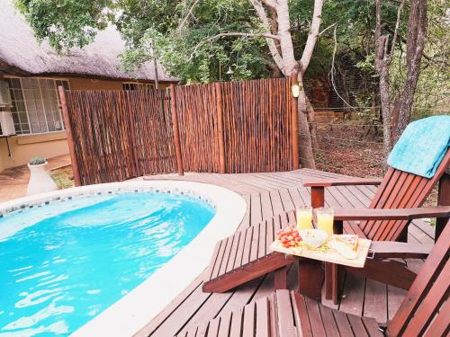 een terras met een tafel en stoelen naast een zwembad bij Treetops Marloth Park in Marloth Park