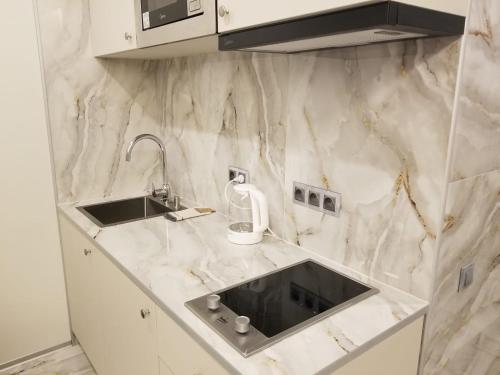 a white marble kitchen with a sink and a microwave at Segreto apartment 309, 311, 341 in Gudauri