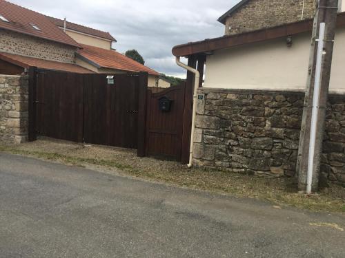 a house with a wooden gate and a stone wall at Lovely French Farmhouse with Private Swimming Pool in Bourganeuf