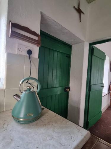 a green bell sitting on a counter in a room with a door at The Lodge at Heathfield House in Ballycastle