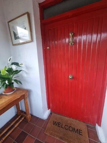 a red door with a welcome mat in front of it at The Lodge at Heathfield House in Ballycastle