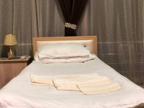 a bed with white sheets and two towels on it at Ikkinchi, keraksiz in Min-Bulak