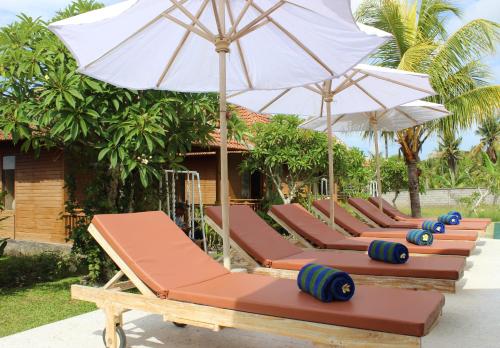 a row of lounge chairs with umbrellas at Green Village Jungle Resort in Nusa Penida