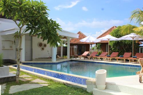a pool at a villa with chairs and umbrellas at Green Village Jungle Resort in Nusa Penida