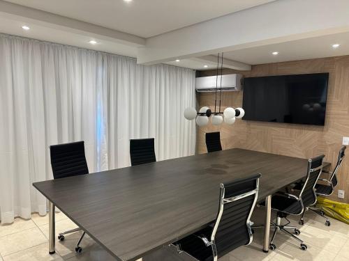 een conferentieruimte met een grote houten tafel en stoelen bij Condominio Club, Vista para o mar, Churrasqueira in Guarujá