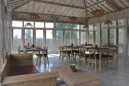 a dining room with tables and chairs and windows at Green Village Jungle Resort in Nusa Penida