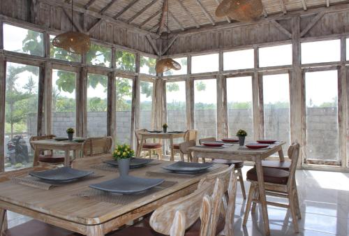 a dining room with tables and chairs and windows at Green Village Jungle Resort in Nusa Penida