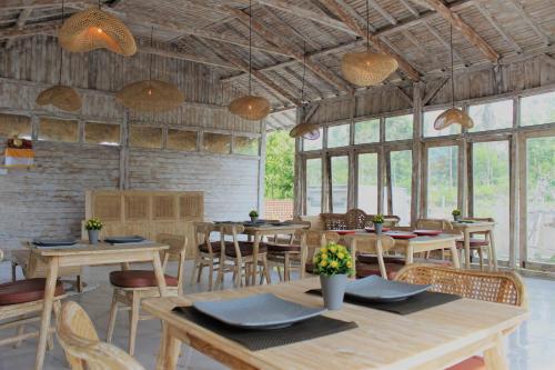 ein Esszimmer mit Tischen, Stühlen und Fenstern in der Unterkunft Green Village Jungle Resort in Nusa Penida