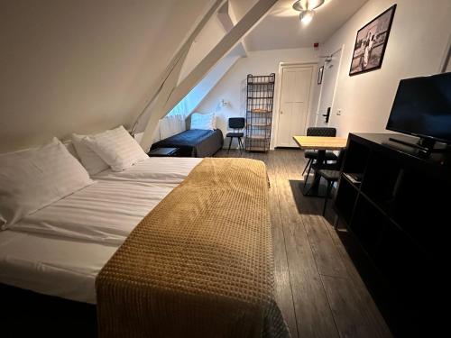 a bedroom with a bed and a desk and a television at Hotel Buren in West-Terschelling