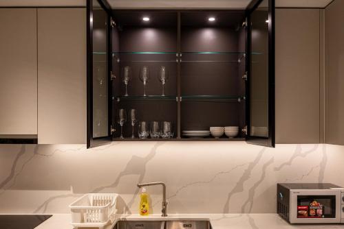 a kitchen with black cabinets and a sink at Metropole Thu Thiem Condo Apartment in Ho Chi Minh City