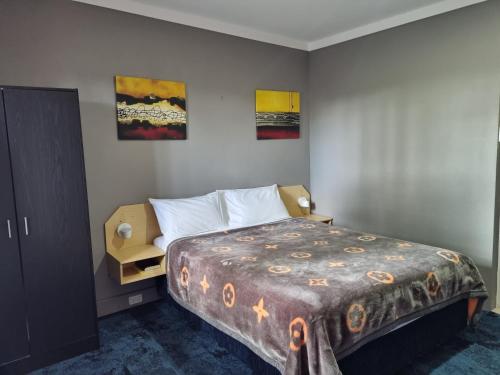 a bedroom with a bed and two paintings on the wall at All Seasons Country Lodge in Taree